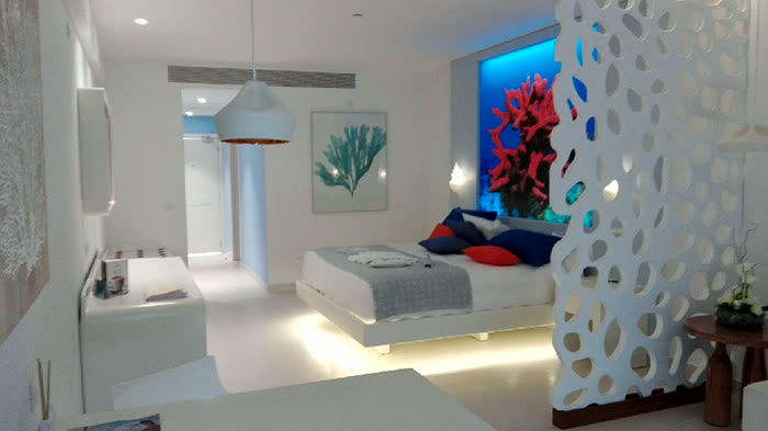Habitación con iluminación arquitectónica: muro de coral retroiluminado y luz indirecta