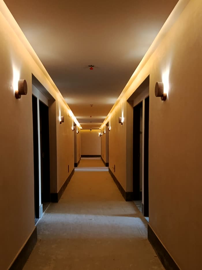 Pasillo de habitaciones con arbotantes y luz de cornisa encendidos