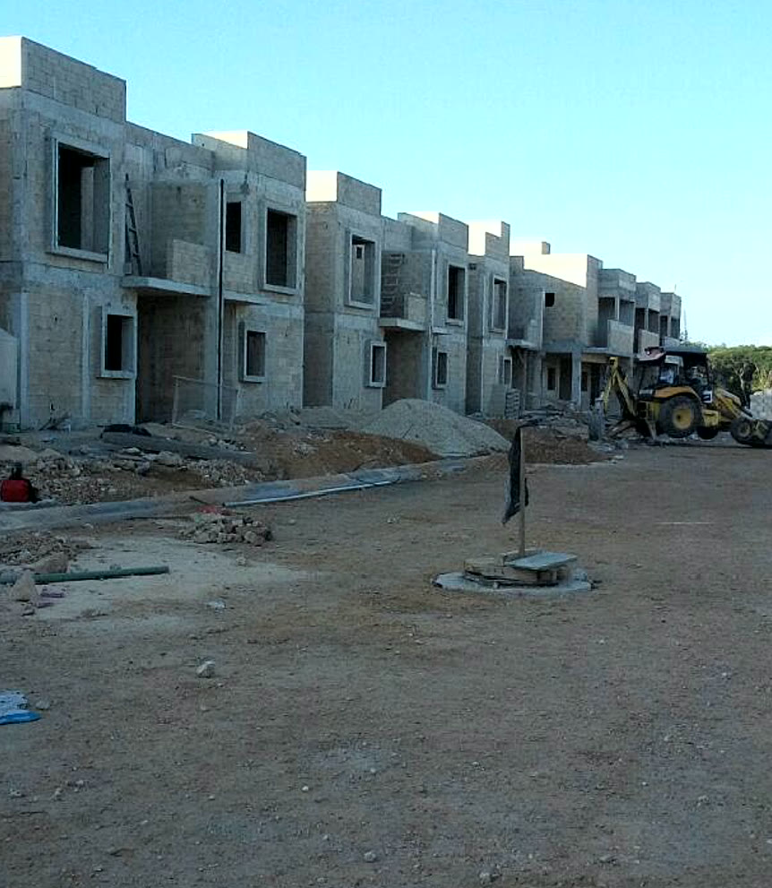 La Joya, hilera de casas en obra gris con la retroexcavadora y el registro eléctrico al frente