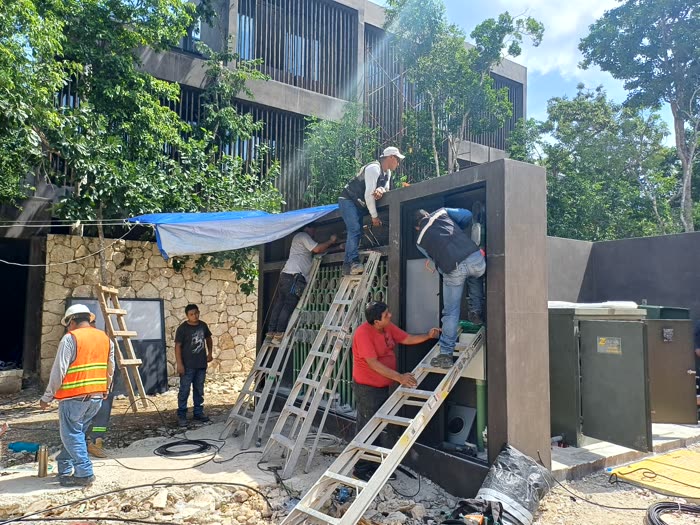 Cuadrilla montando los tableros del muro de acometida, con el transformador pad-mounted al lado