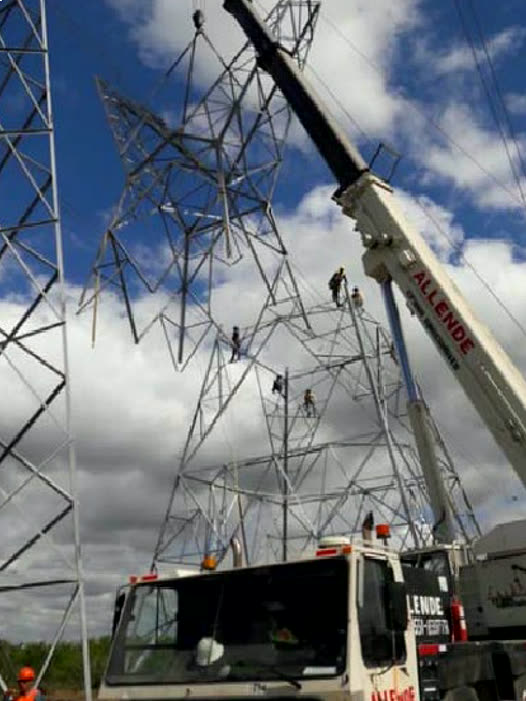 Montaje de una torre de transmisión con grúa y torristas en la estructura