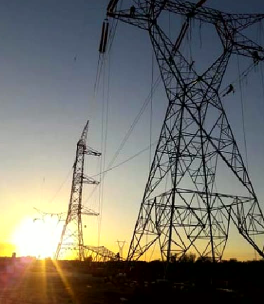 Línea de alta tensión al atardecer, torres de transmisión con torristas en la estructura
