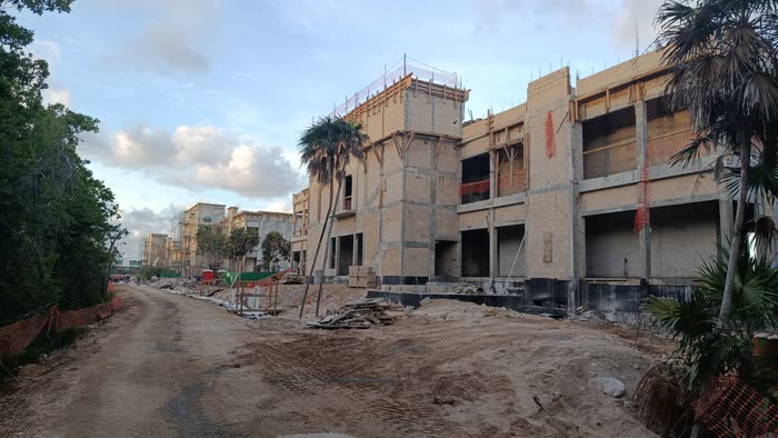 Edificios del Valentín Imperial en obra gris, con palmeras y camino de terracería