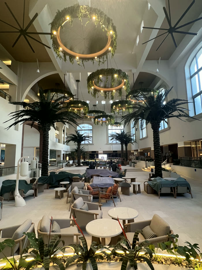 Lobby del hotel con candiles de anillo y palmeras bajo el tragaluz